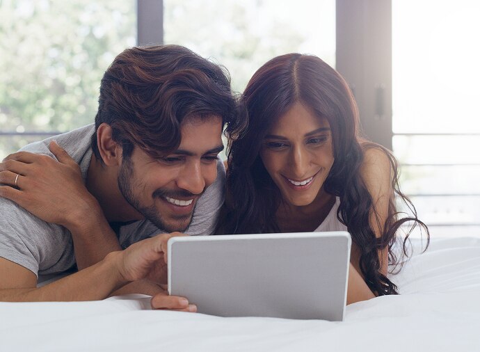Mann und Frau schauen auf ein Tablet und lachen
